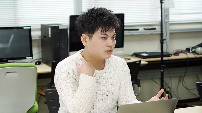 Takayuki Kameoka sitting down in front of a laptop wearing a white shirt.