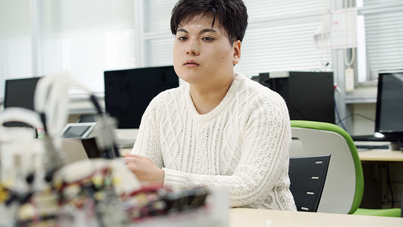 Takayuki Kameoka sits wearing a white shirt.