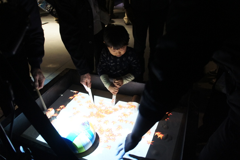 A box is shown with images projected on to the top of the sand by projection mapping
